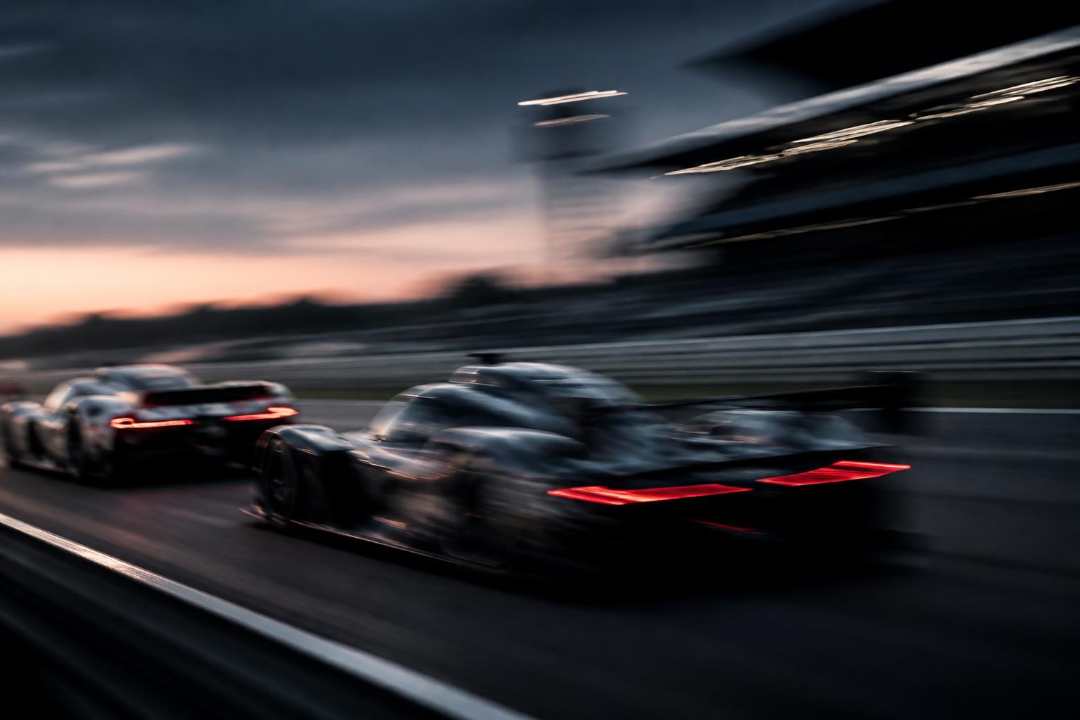 Race cars on circuit at dusk